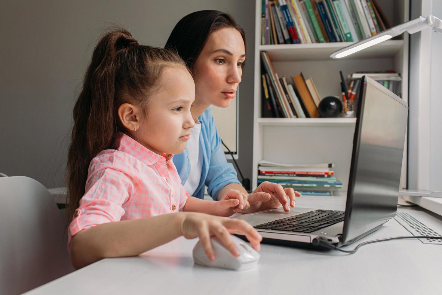 Mutter und Tochter richten Laptop für virtuelle Schule ein foto