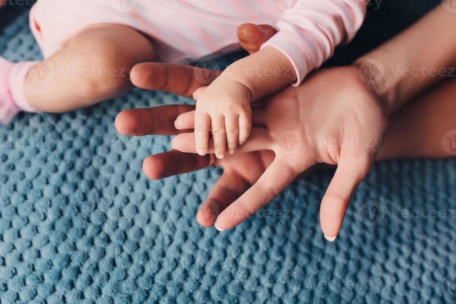 Mama und Papa halten Babys Hand. Kindergriff foto