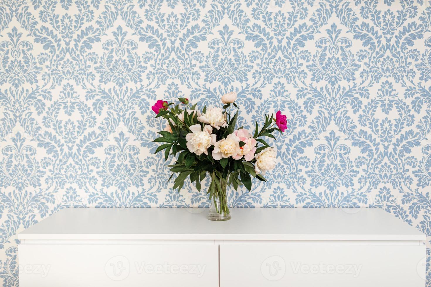 Pfingstrosen frische Schnittblumen in einer Vase mit Kopienraum auf einem weißen Tisch auf blauem Hintergrund. foto