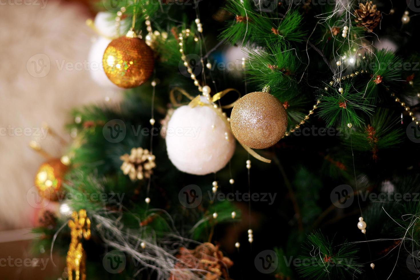 Weihnachtsfeiertag Hintergrund. goldene und weiße Kugeln, die an einem geschmückten Baum mit Bokeh hängen, kopieren Raum foto