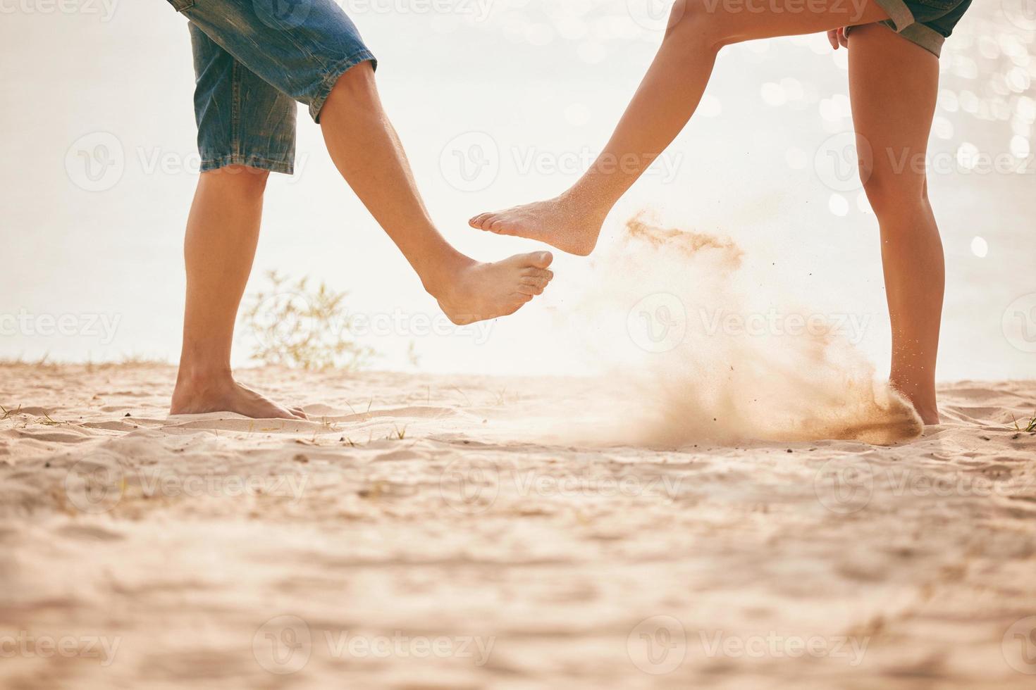 junges Paar spielt mit Sand. Sommer Lebensstil. Füße im Sand am Strand foto