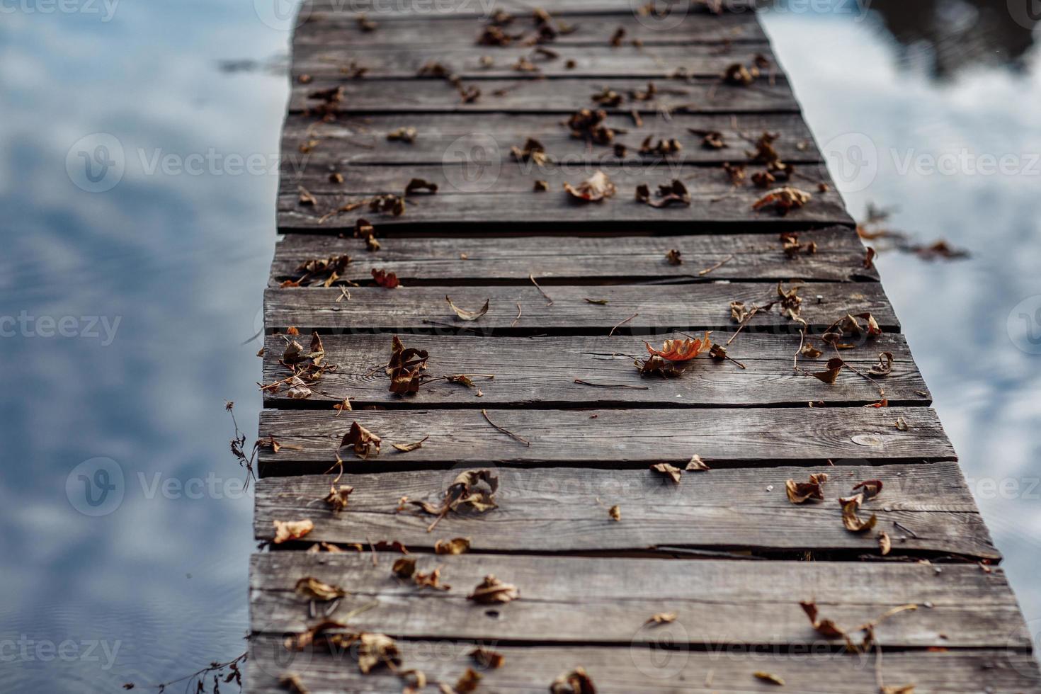 Eine Holzbrücke ist mit Herbstlaub bedeckt. Herbstahornblätter auf Holztisch. fallender natürlicher Hintergrund der Blätter foto