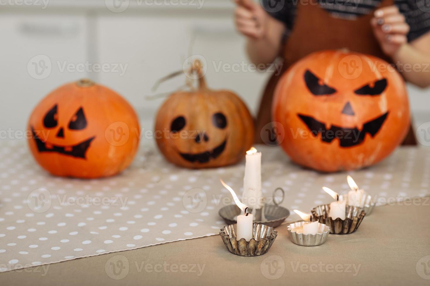 brennende Kerzen schließen auf einem Hintergrund von Kürbissen. Halloween Kürbiskopf Jack Laterne mit brennenden Kerzen. beleuchtete Halloween-Kürbisse mit Kerzen in der Küche foto