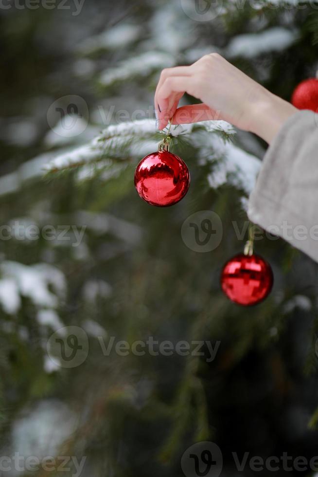 Frau, die Weihnachtsverzierung hält. Mädchen schmückt Weihnachtsbaum in einem Haus. Feiertagsfeier. die Grüße der Jahreszeit. foto