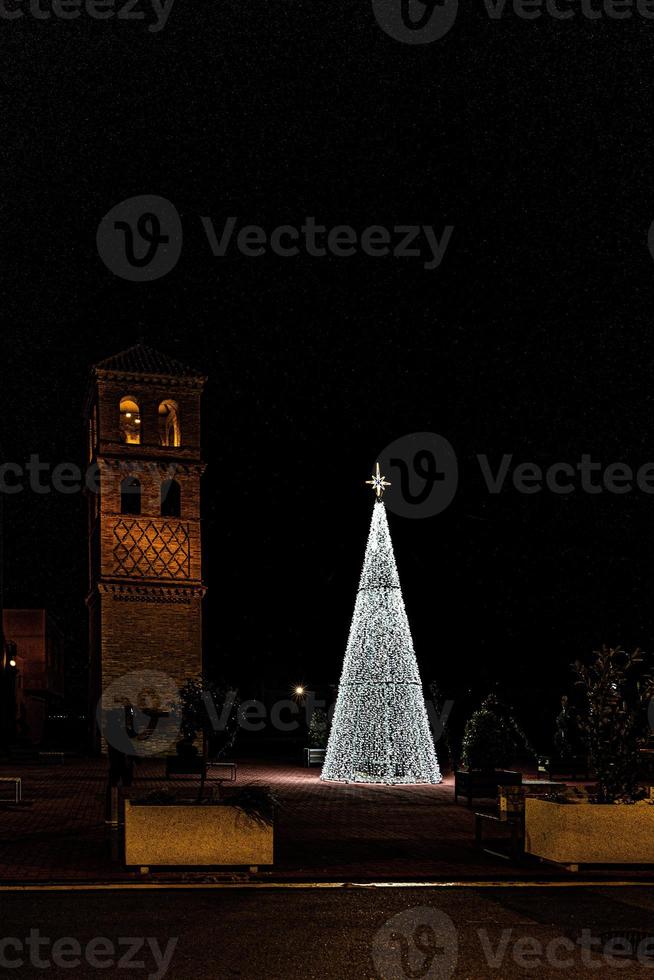 leuchtend Weihnachten Baum Dekoration auf ein Nacht Hintergrund von ein Spanisch Stadt, Dorf foto