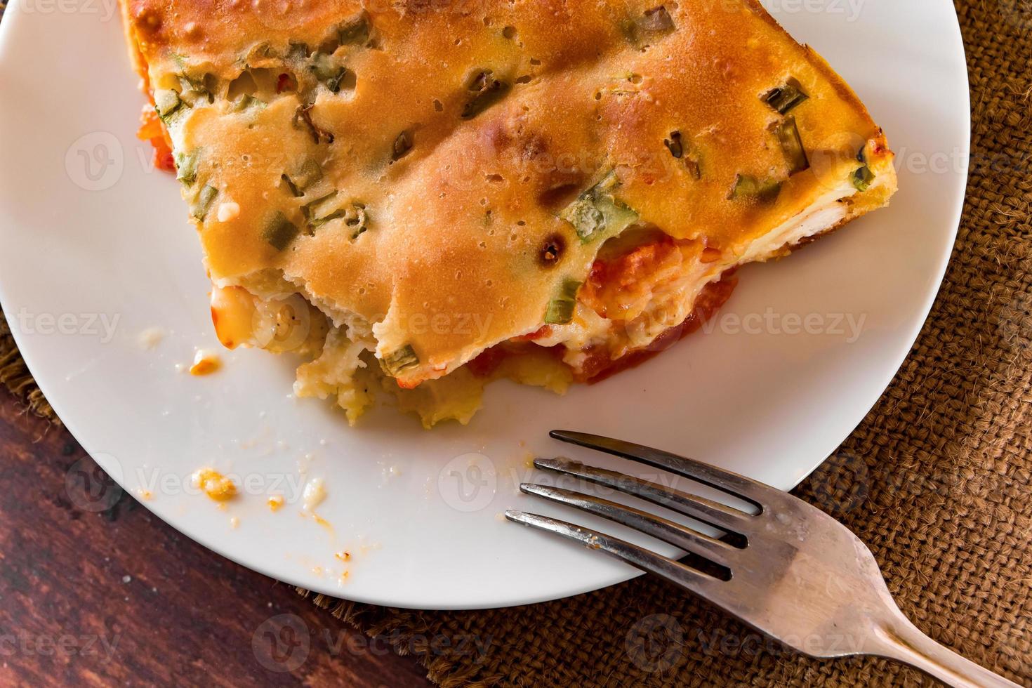 hausgemachte Torte mit Huhn, Kräutern und Tomaten auf einem Teller foto