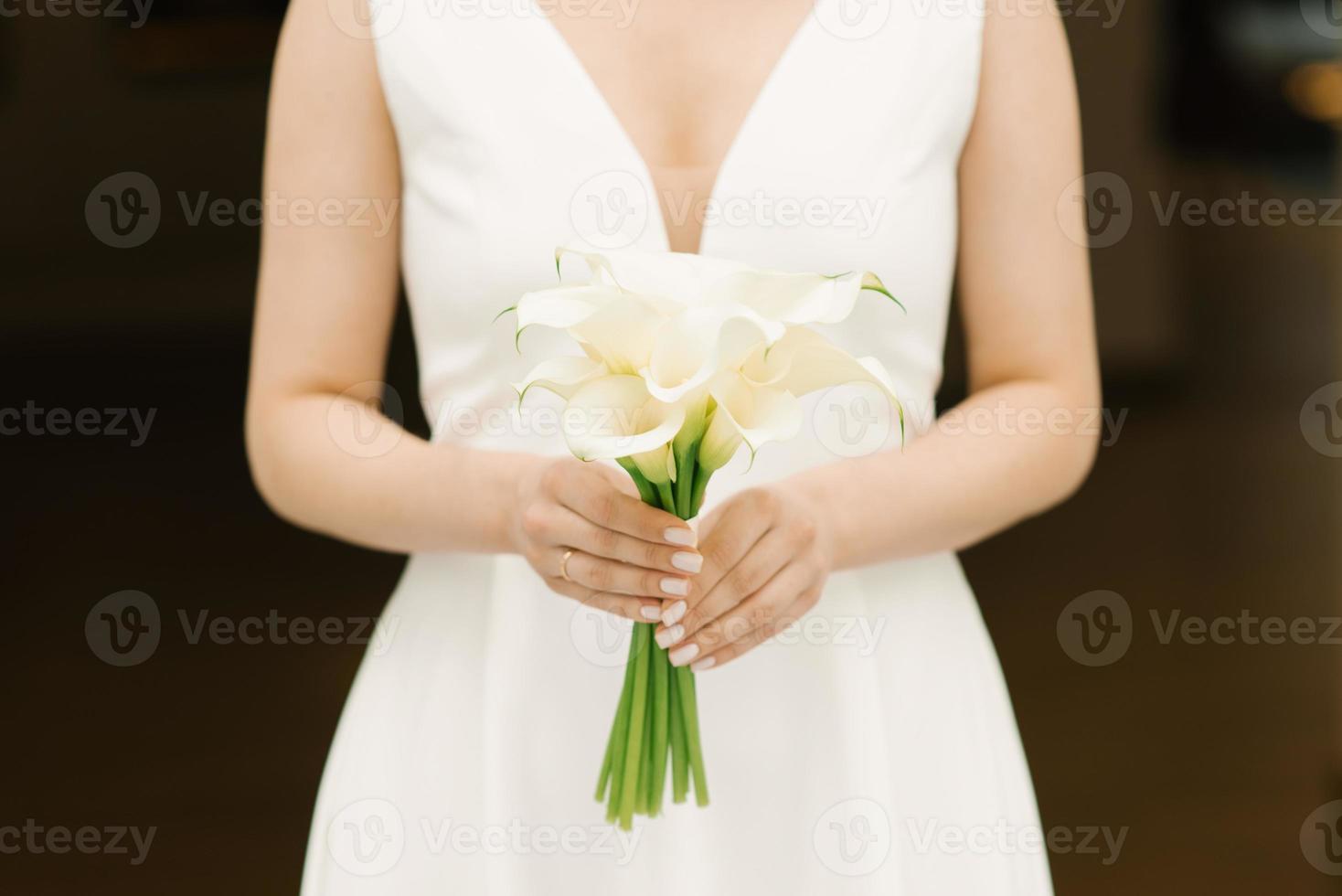 Zarter weißer Strauß Calla-Lilien in den Händen der Braut bei der Hochzeit foto