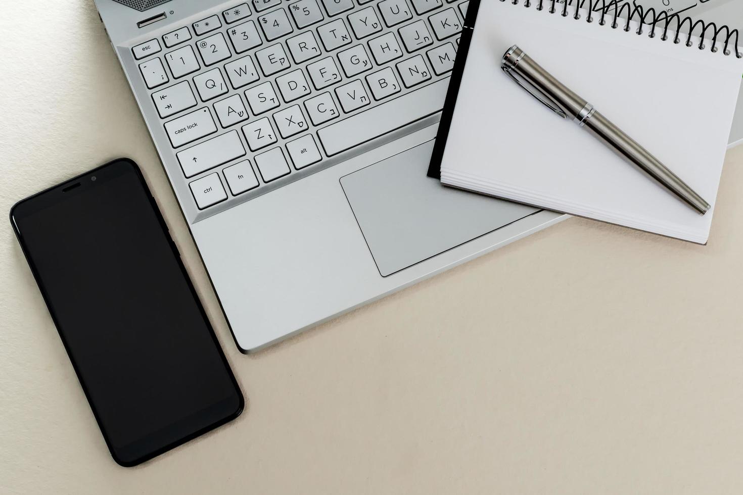 Draufsicht auf einen Schreibtisch mit Laptop, Notebook, Stift und Handy. foto