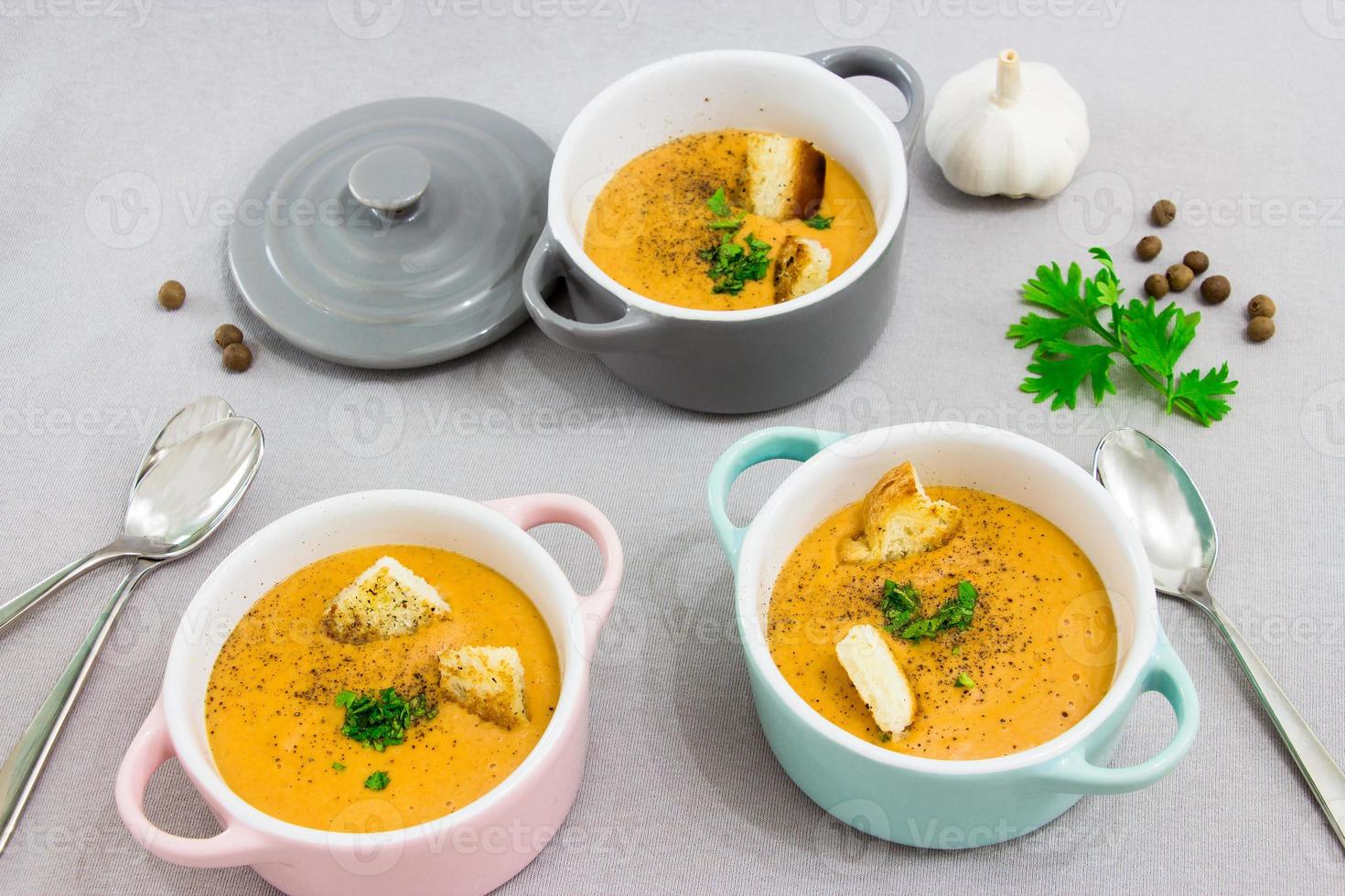 drei kleine Serviertöpfe oder Schalen mit Sahnesuppe aus roten Linsen mit Zwieback, Gewürzen und Kräutern, Petersilie und Koriander. auf einem hellgrauen Hintergrund. foto