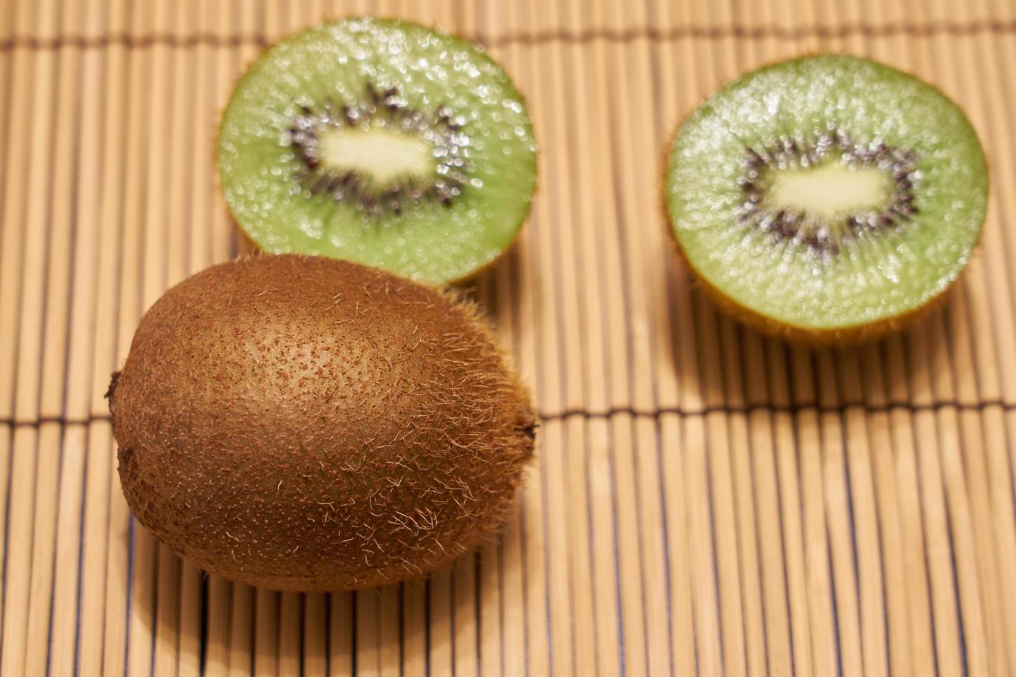 reife braune Kiwi mit geschnittener grüner Kiwi auf einem Strohhintergrund mit Platz für Text. foto