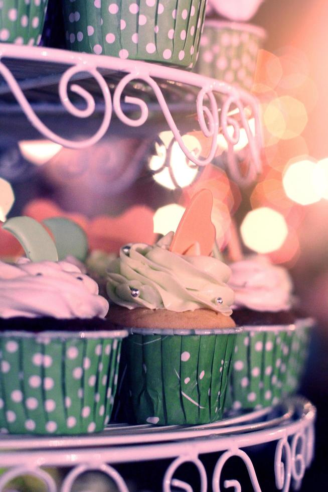 Hochzeit Cupcakes mit bunt Sträusel im Grün Tasse mit Girlande Beleuchtung Bokeh Hintergrund foto