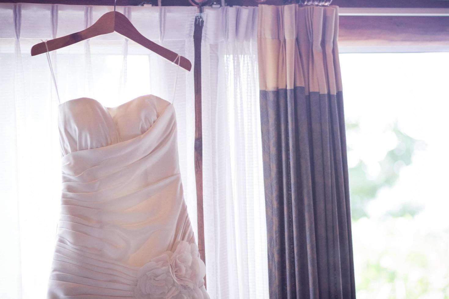 Hochzeit Kleid hängend auf Vorhang Schiene in der Nähe von Fenster im Zimmer foto