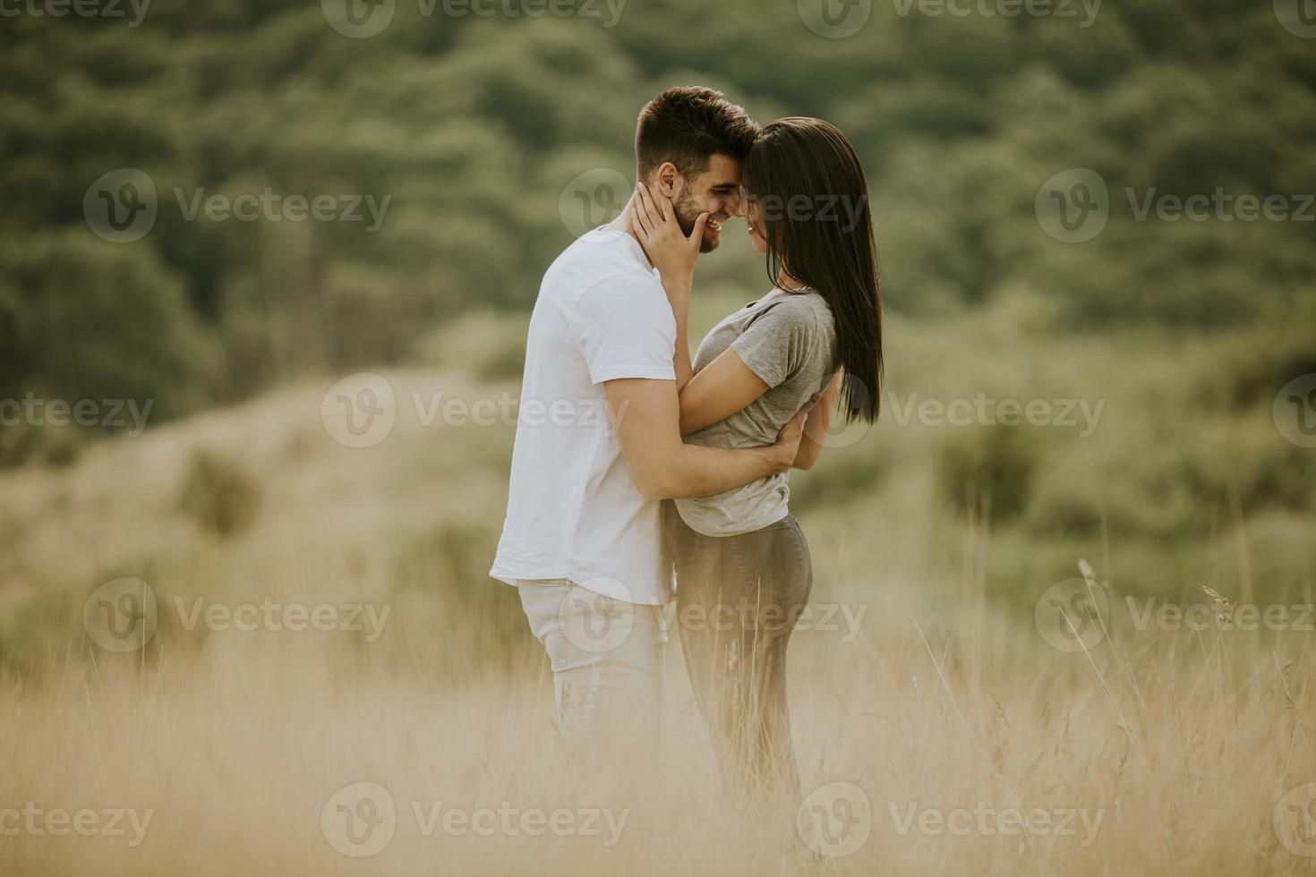 glückliches junges Paar in der Liebe, die durch Grasfläche geht foto