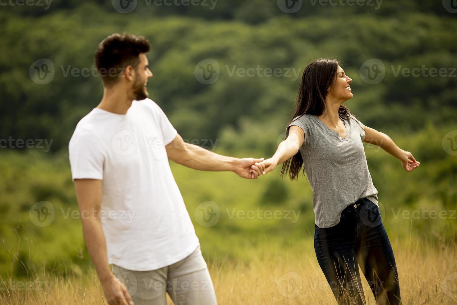 glückliches junges Paar in der Liebe, die durch Grasfläche geht foto