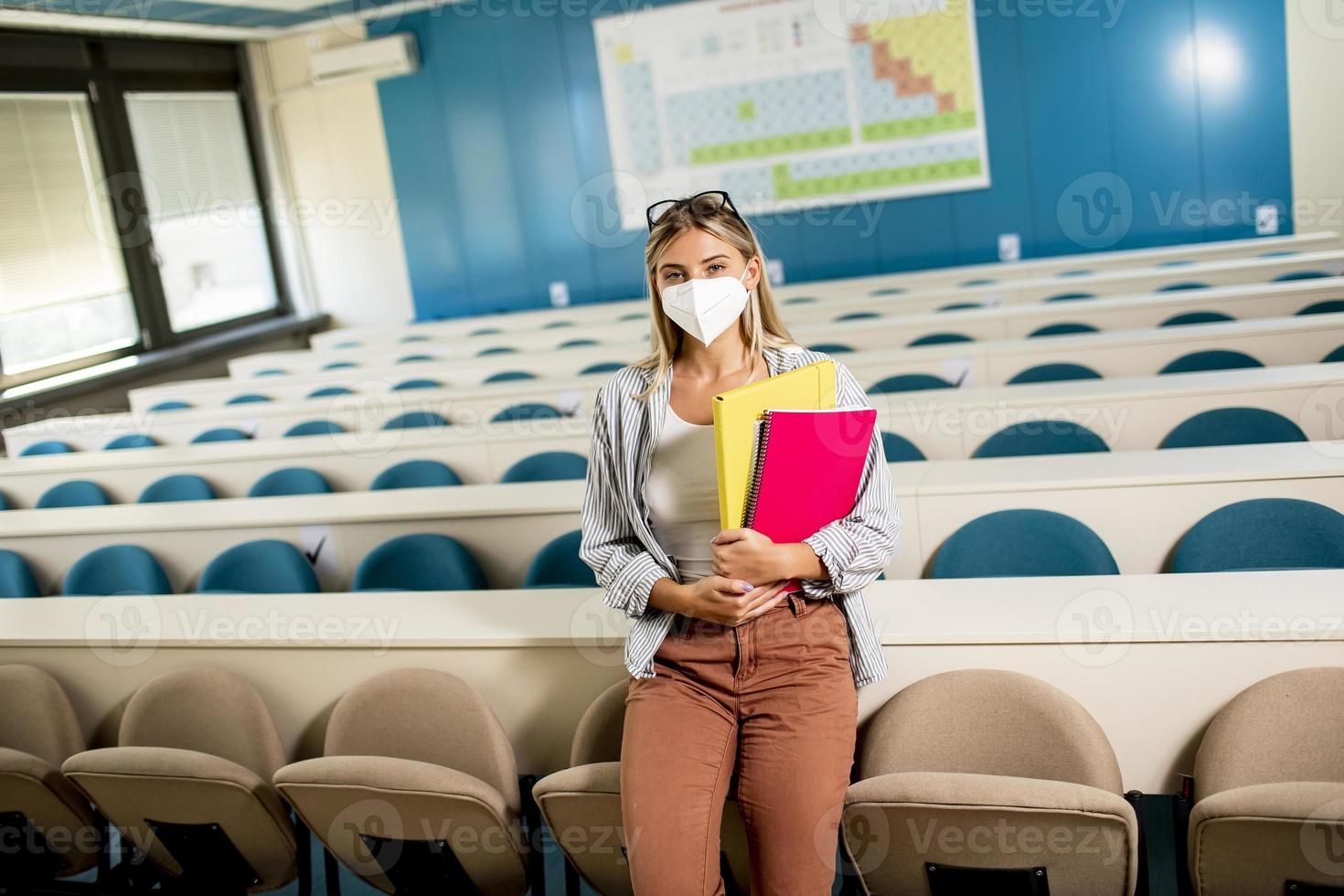 Studentin mit Gesichtsschutzmaske für Virenschutz im Hörsaal foto