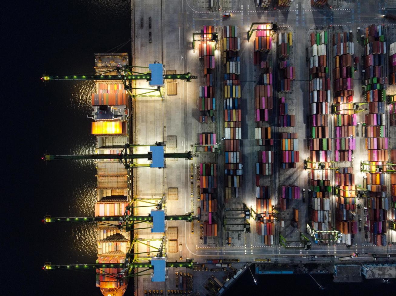 Jakarta, Indonesien 2021 - Luftaufnahme des Be- und Entladens von Containerschiffen im Tiefseehafen, logistischer Import und Export von Frachttransporten mit Containerschiffen auf offener See bei Nacht foto