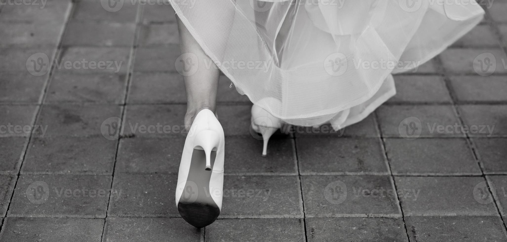 Nahansicht von weiblich Absätze von ein Braut im ein Hochzeit Kleid foto