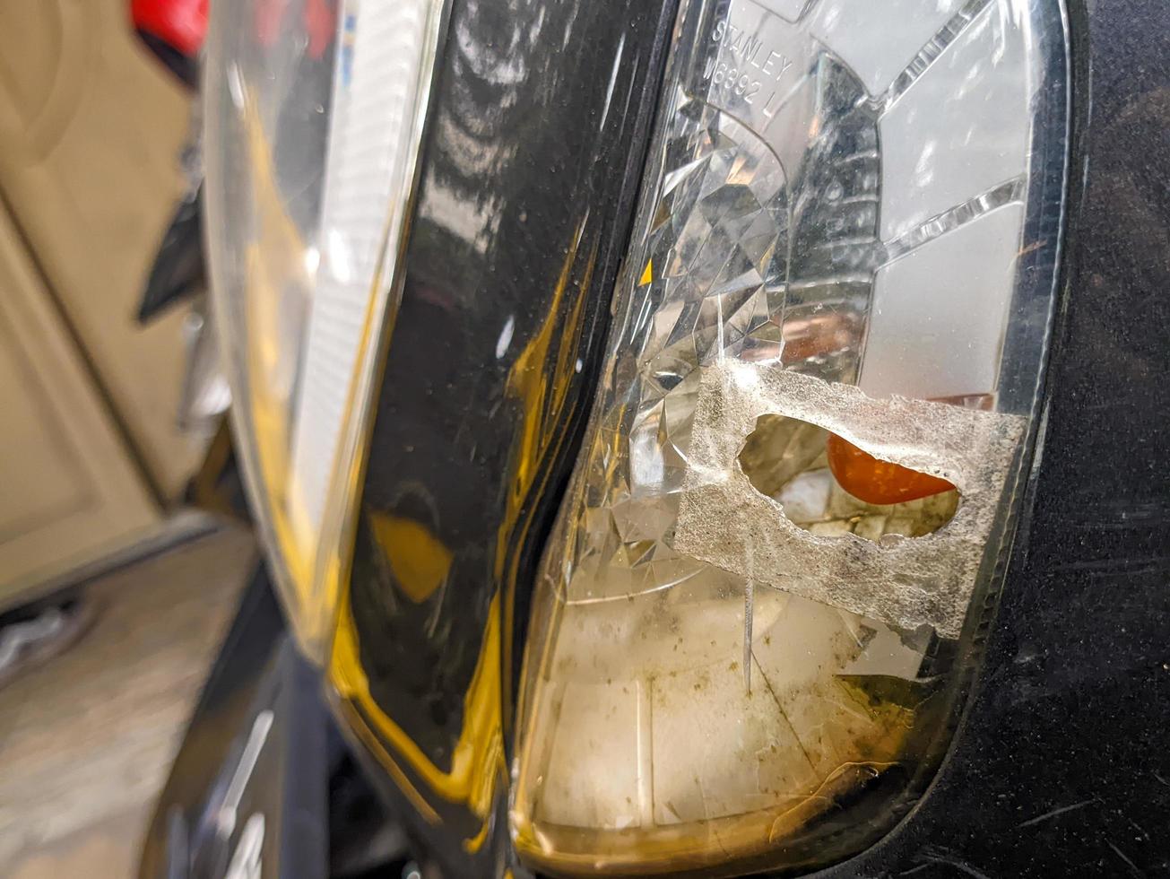ein schließen oben von perforiert, beschädigt oder gebrochen Motorrad Scheinwerfer Glas foto