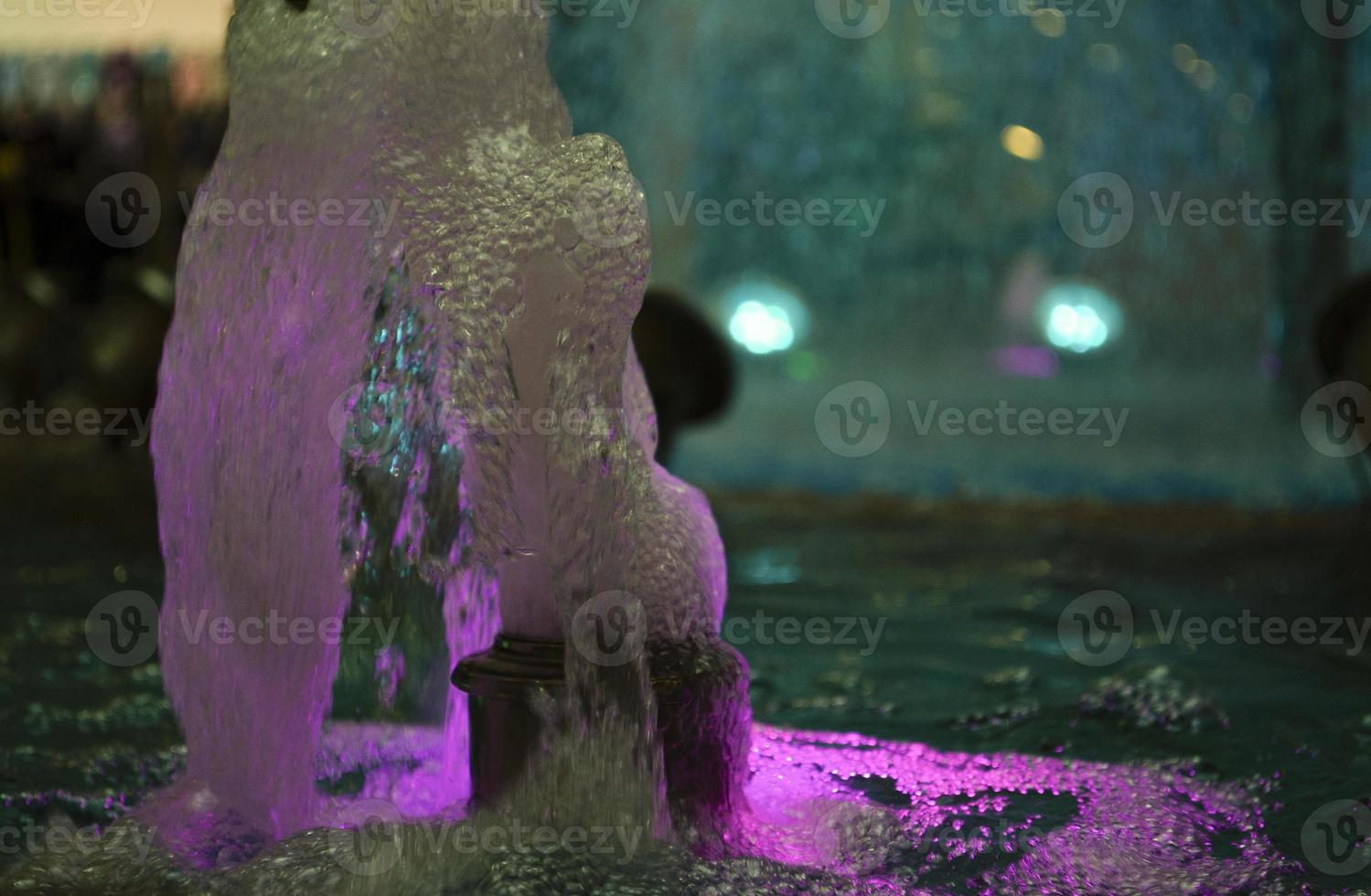 verschwommen Wasser Hintergrund. von hinten beleuchtet Wasser Jet im das Brunnen. foto