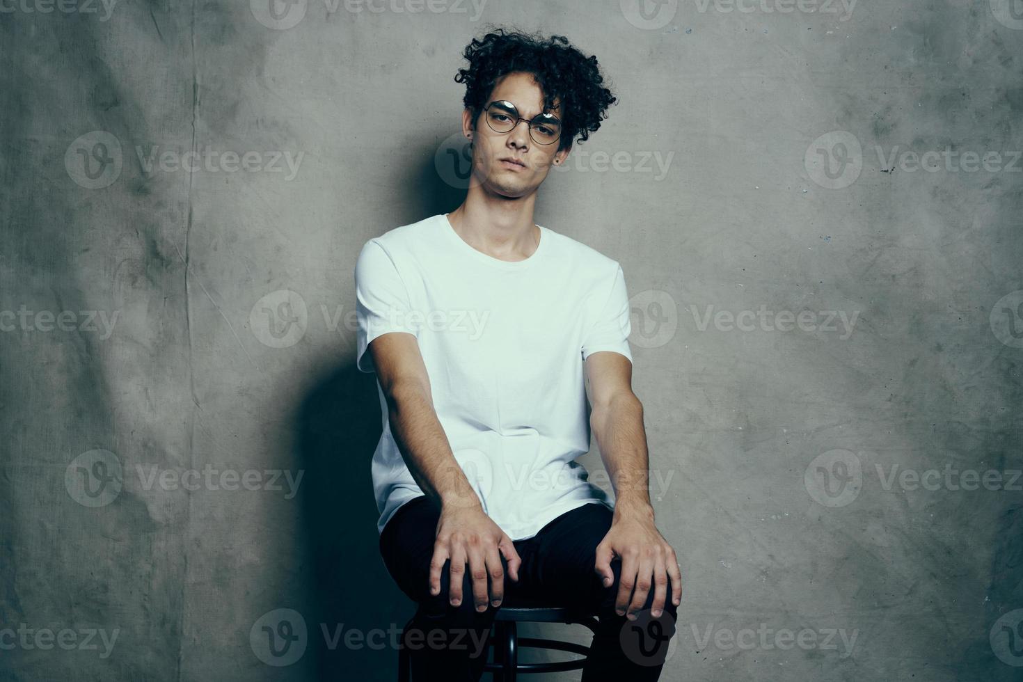 Mann mit lockig Haar Brille Weiß T-Shirt Studio Mode foto