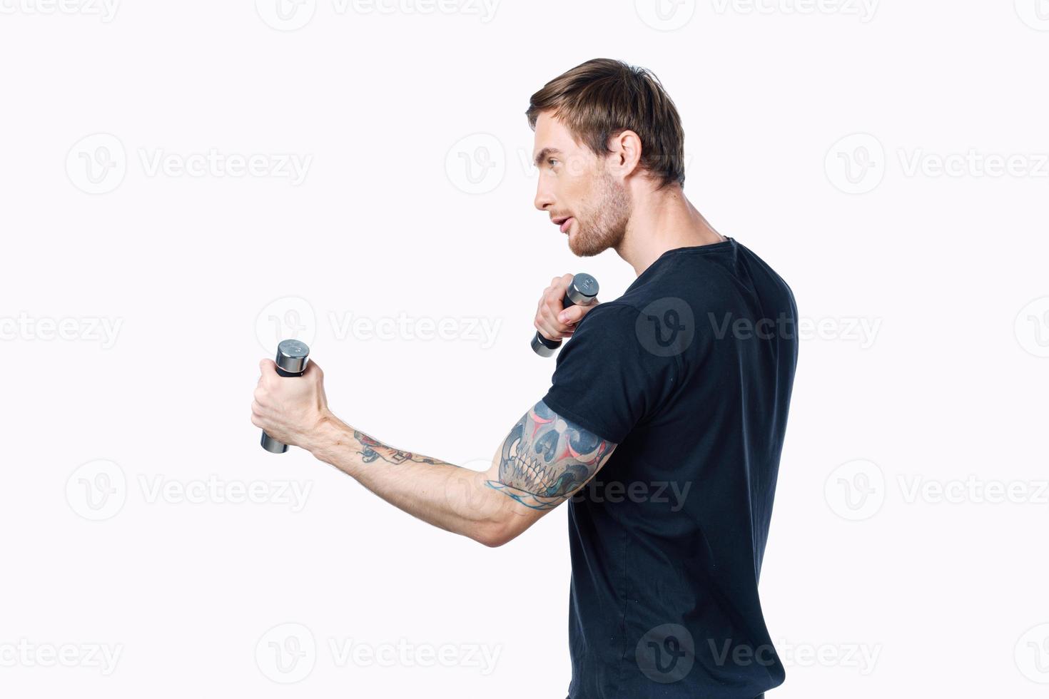 Athlet mit Hanteln ist beschäftigt, verlobt im Fitness auf ein Licht Hintergrund drinnen Seite Aussicht foto