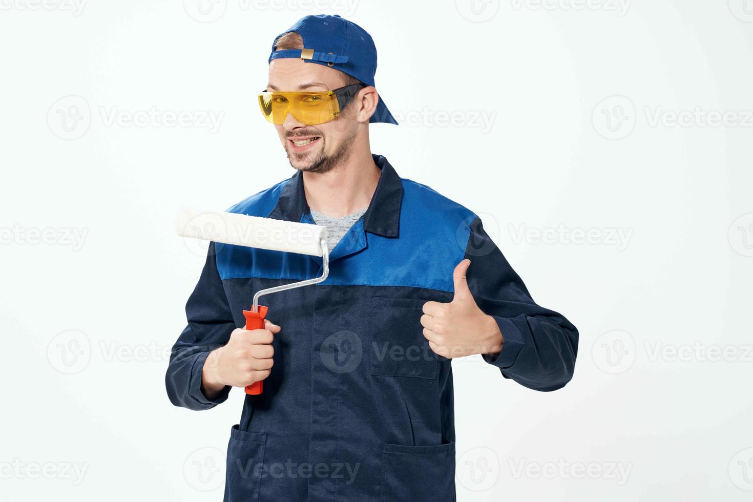 ein Mann im ein Arbeiten Uniform ein Walze zum Gemälde Wände im seine Hände Dekoration Reparatur foto