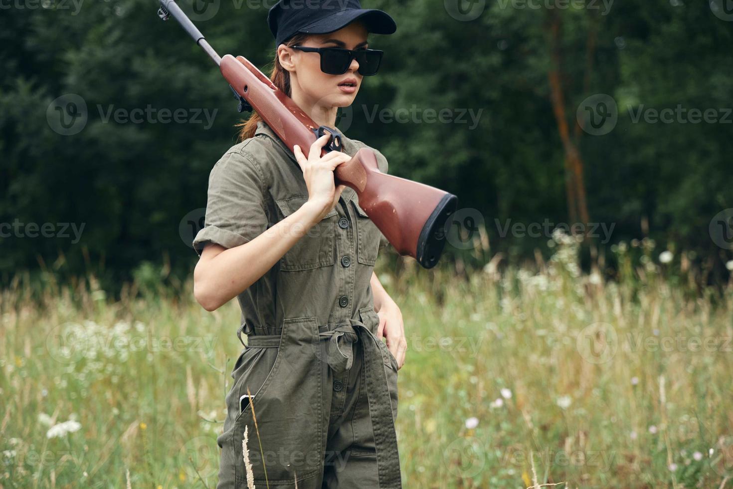 Frau auf draussen Waffen auf Schultern Sonnenbrille Grün Overall Jagd foto