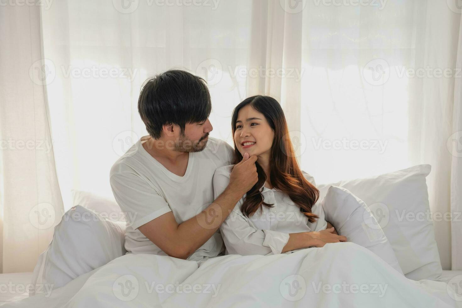 glücklich jung asiatisch Paar umarmen, neckisch, spielen fröhlich im Bett beim heim, romantisch Zeit zu verbessern Familie Verbindung. Familie Konzept. foto