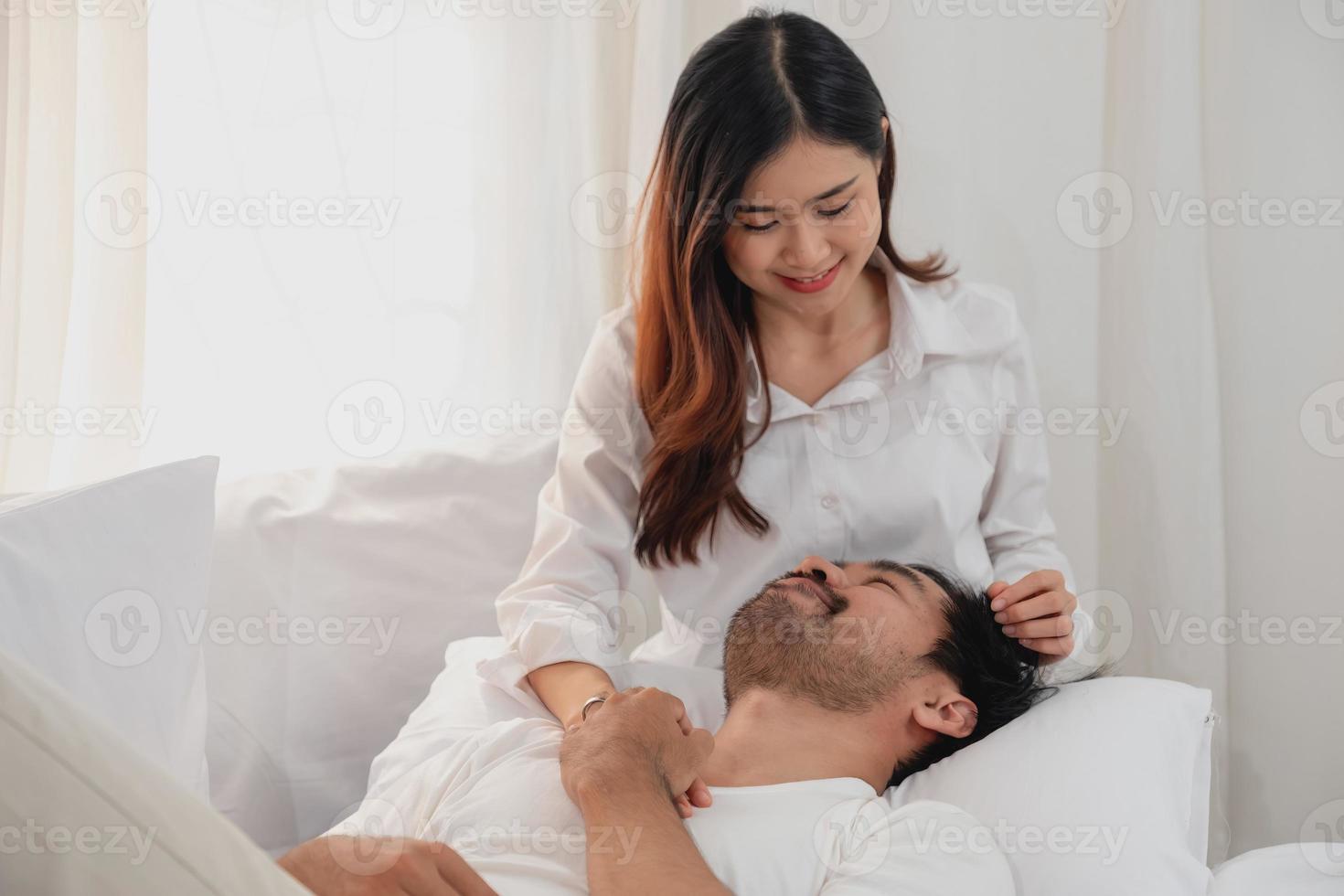 glücklich jung asiatisch Paar umarmen, neckisch, spielen fröhlich im Bett beim heim, romantisch Zeit zu verbessern Familie Verbindung. Familie Konzept. foto