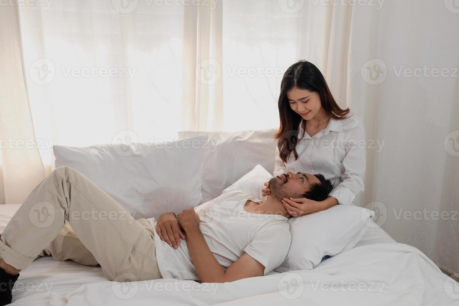 glücklich jung asiatisch Paar umarmen, neckisch, spielen fröhlich im Bett beim heim, romantisch Zeit zu verbessern Familie Verbindung. Familie Konzept. foto