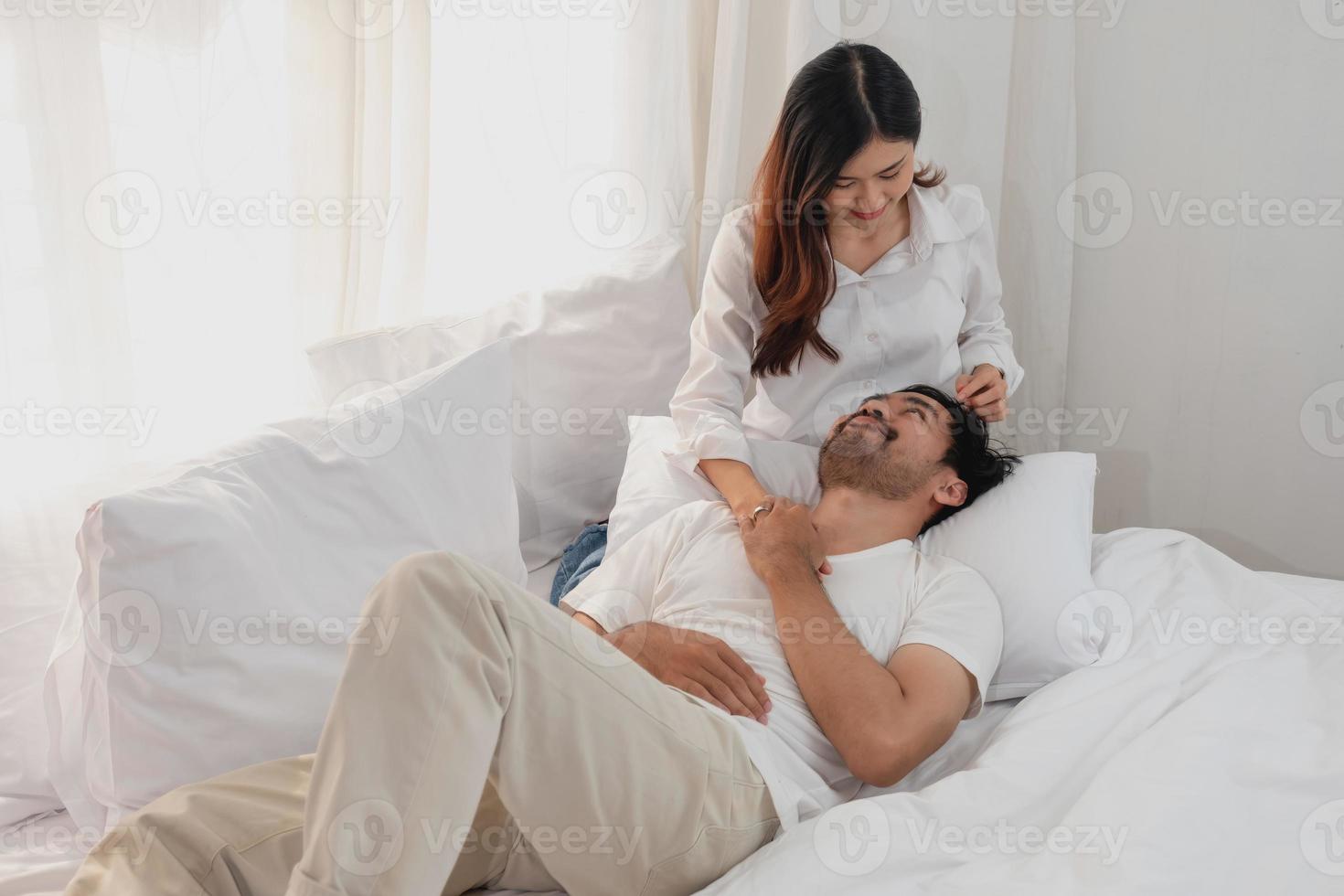 glücklich jung asiatisch Paar umarmen, neckisch, spielen fröhlich im Bett beim heim, romantisch Zeit zu verbessern Familie Verbindung. Familie Konzept. foto