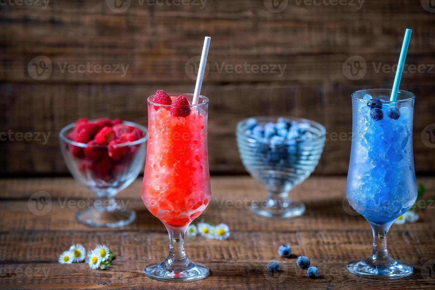 Sommer- sizilianisch Granit Nachtisch, gefroren Himbeeren, Blaubeere Saft im groß Glas Brille auf ein hölzern Hintergrund mit frisch Beeren. Sommer- Cool, Tonic zerquetscht Eis Cocktail foto