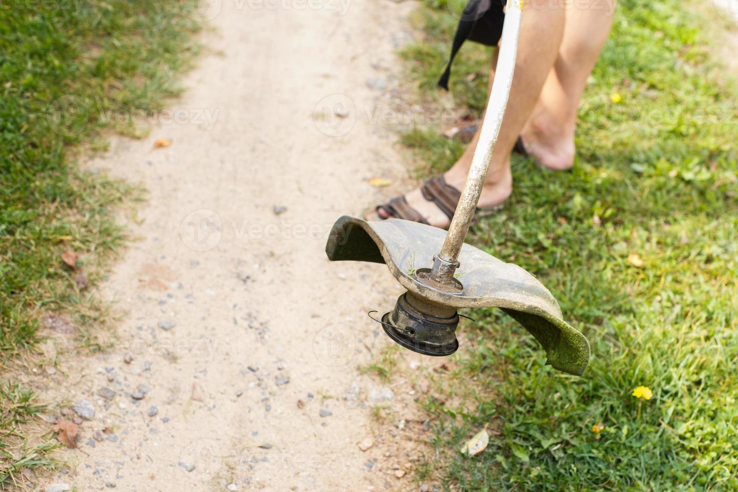 ein Mann mäht Gras mit ein Trimmer draussen foto