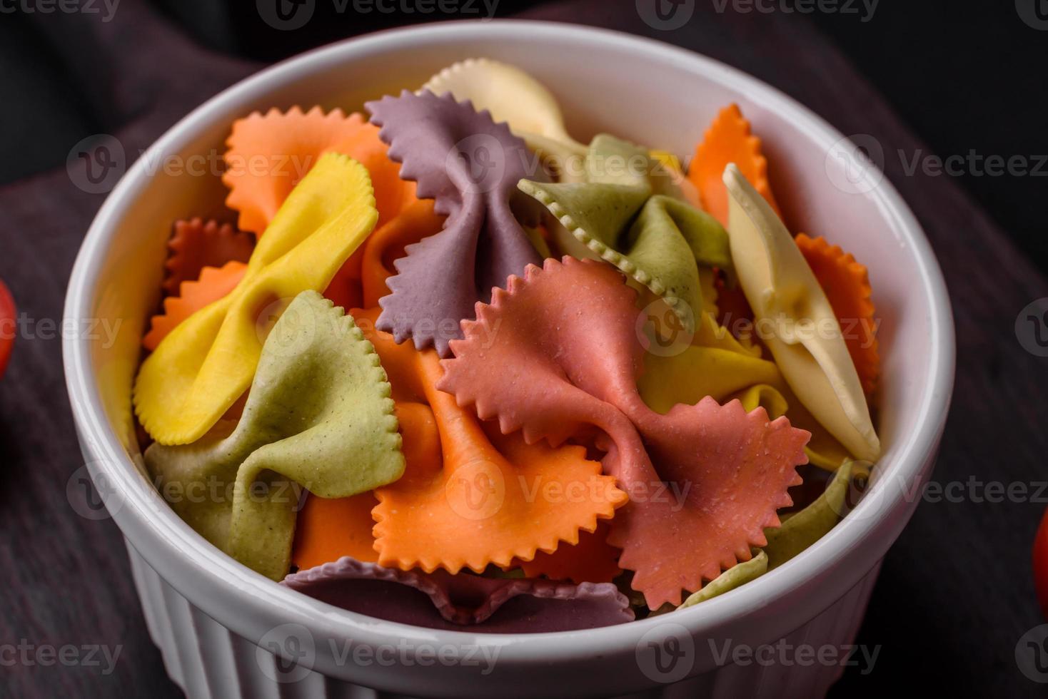 roh farfalle Pasta im anders Farben auf ein dunkel Beton Hintergrund foto