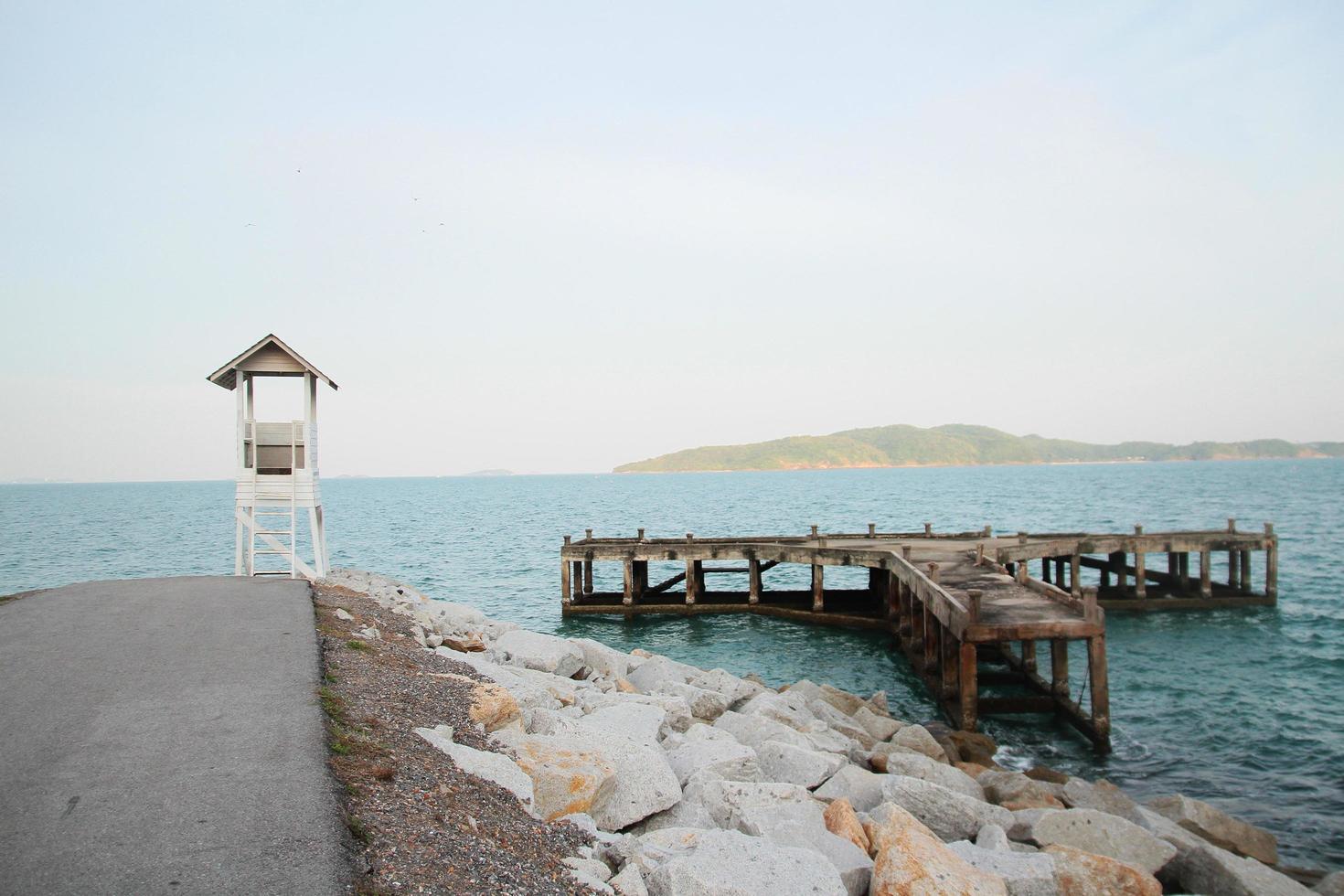 Weiß Rettungsschwimmer Turm und alt hölzern Brücke mit Seelandschaft Aussicht auf das Strand im Thailand foto