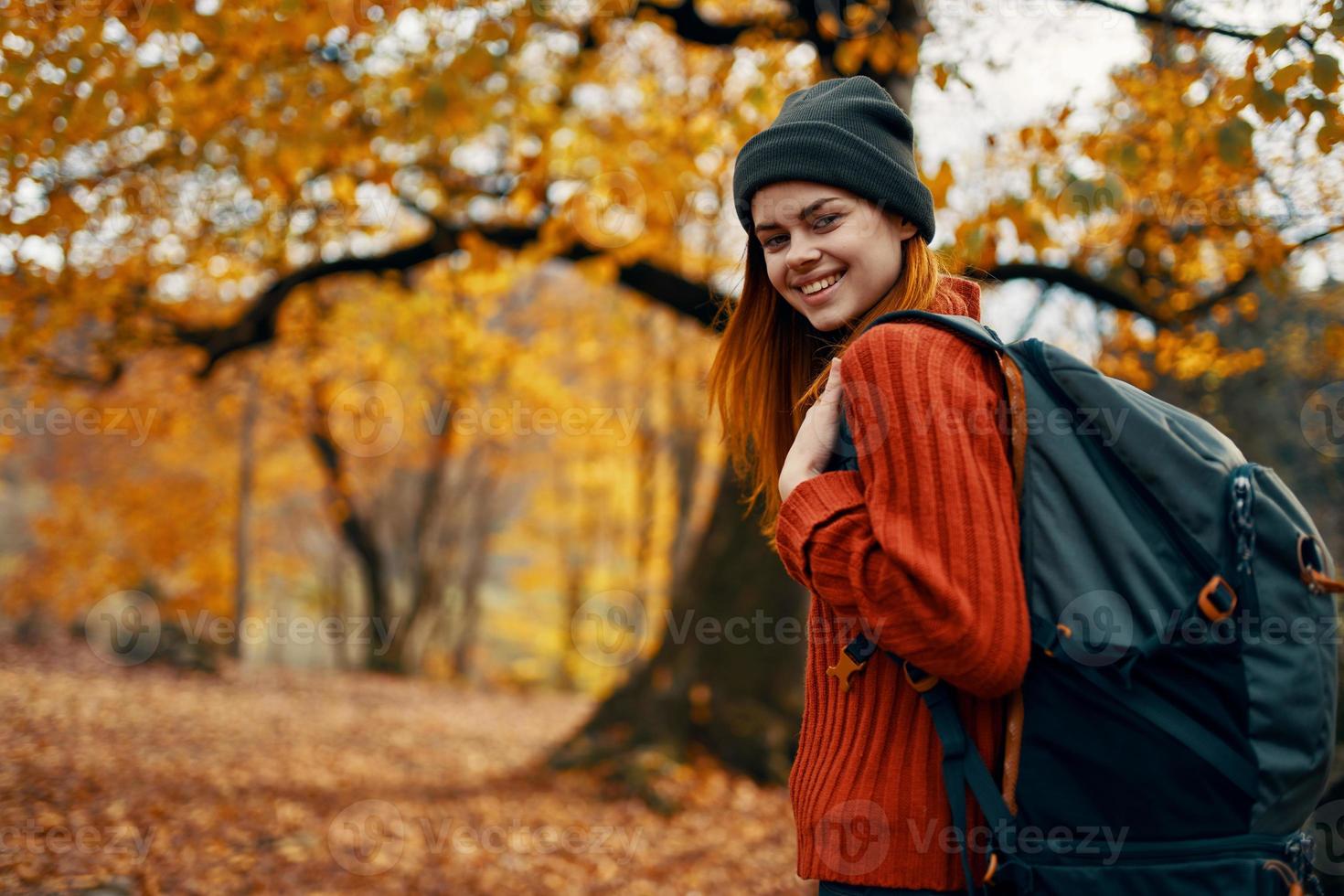 glücklich Frau mit Rucksack Gehen im Park im Natur im Herbst abgeschnitten Aussicht foto
