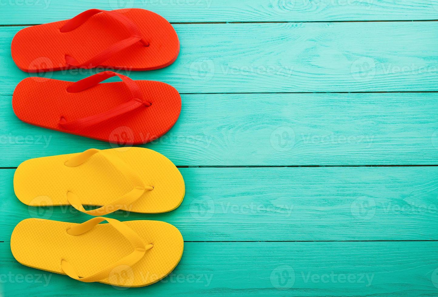 Bunte Flip-Flops auf blauem Holzhintergrund mit Kopierraum. Ansicht von oben foto