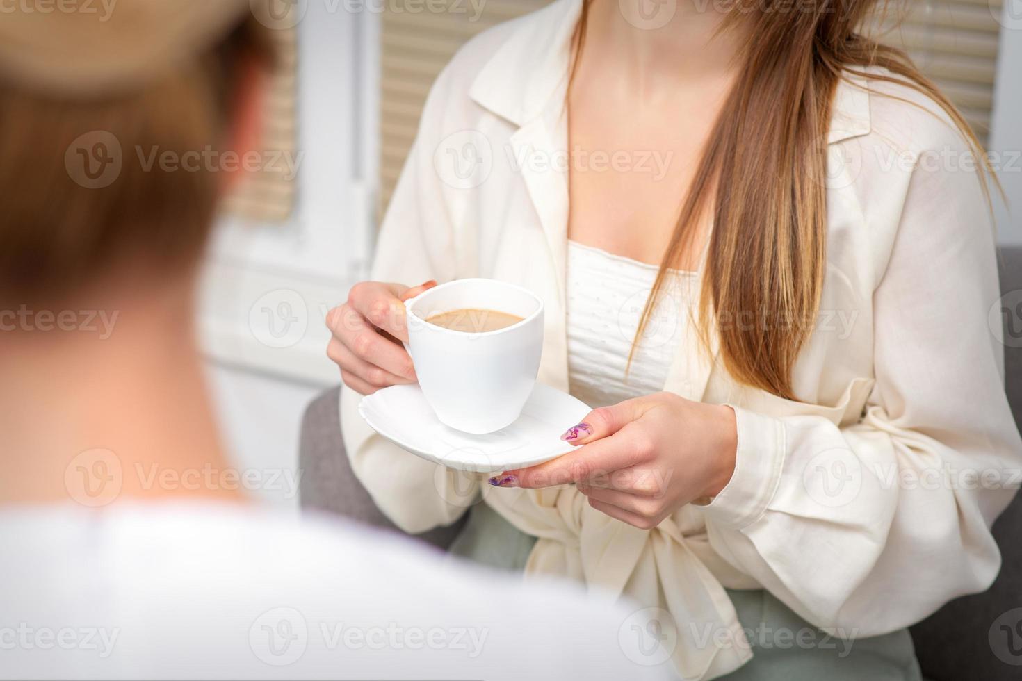 jung kaukasisch unkenntlich Frau halten ein Tasse von heiß trinken beim ein Arzt geplanter Termin im Krankenhaus Büro. foto