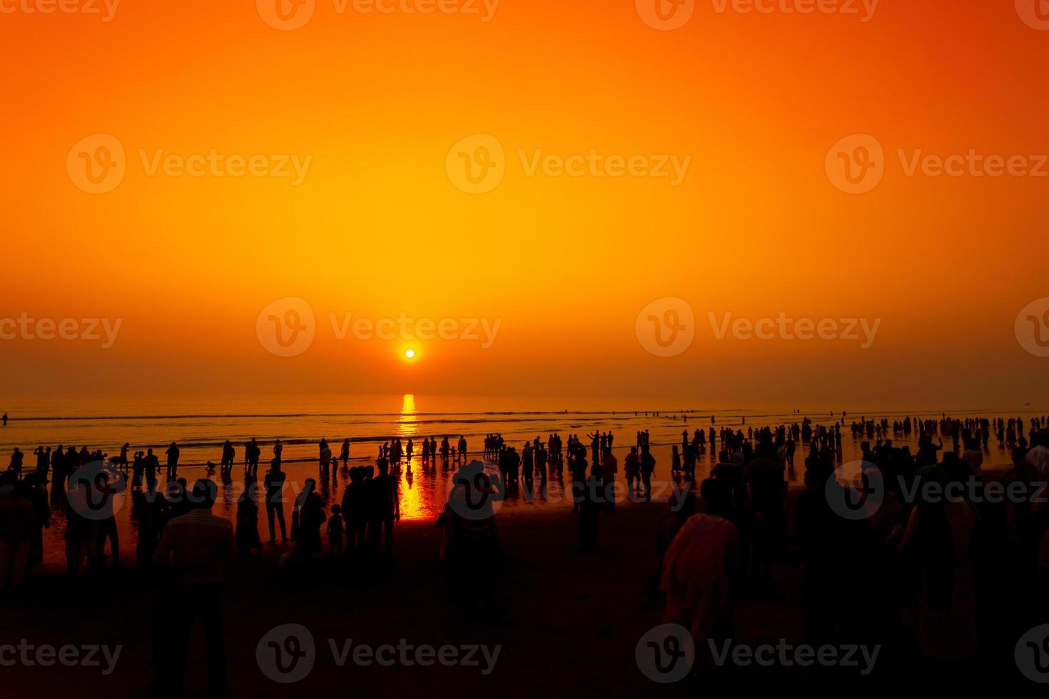 Menge von Silhouette Menschen Gehen auf das am längsten Strand während Sonnenuntergang beim Chattogramm. foto