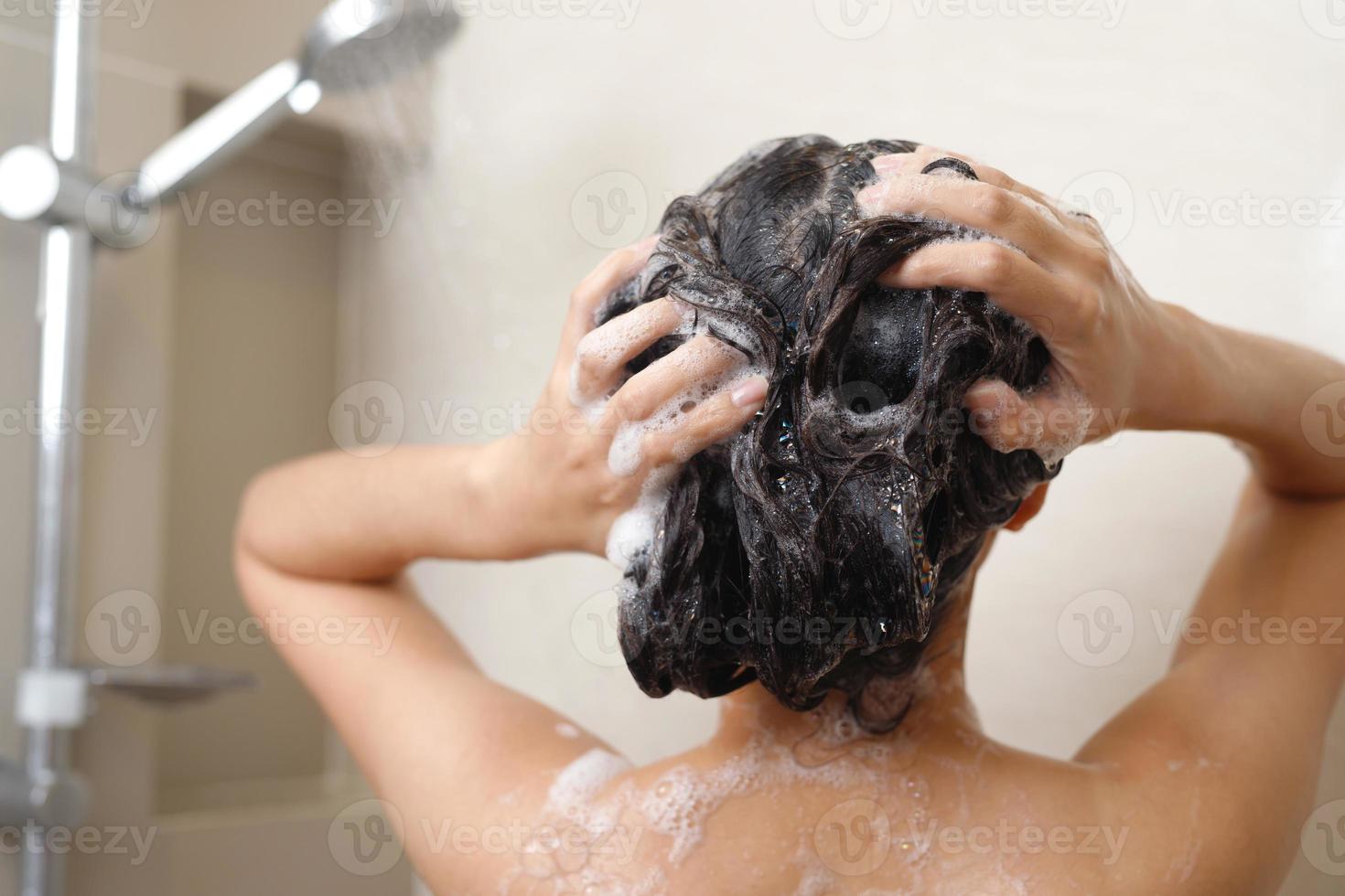 Frau nehmen Dusche und Waschen Haar mit Shampoo foto