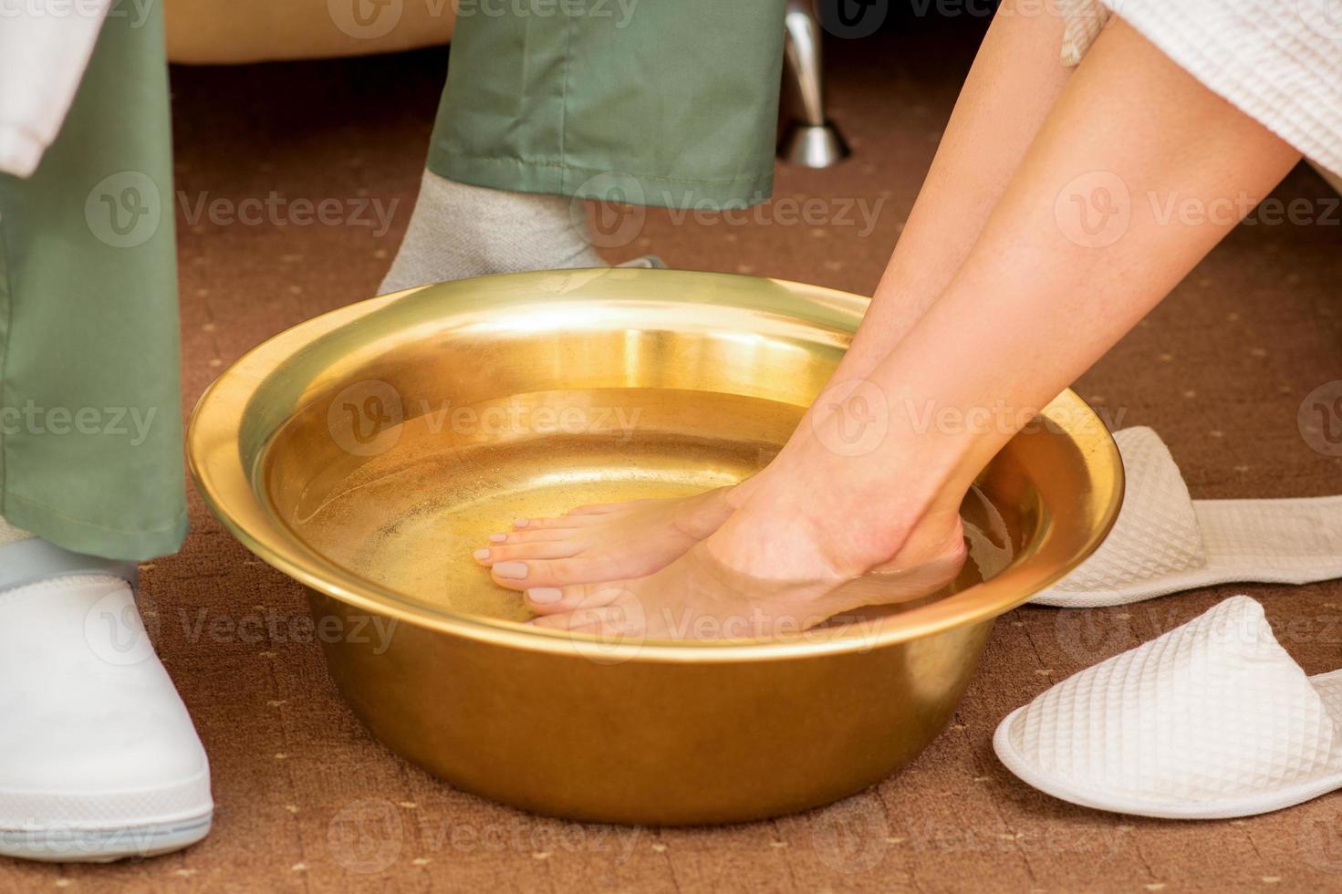 weiblich Füße im ein golden Schüssel mit Wasser im Spa Salon. Spa Behandlung. foto