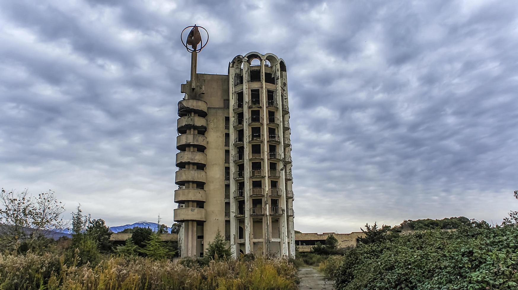 Ein hohes verlassenes Gebäude mit einem wolkigen blauen Himmel im Dorf Esher, Abkhazia foto