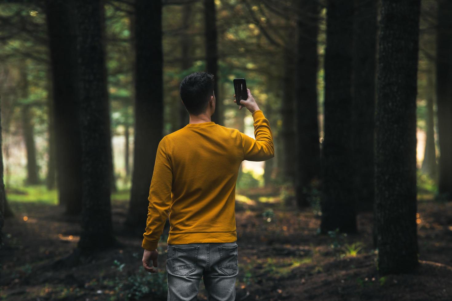 Person im Wald, die Fotos mit dem Telefon macht
