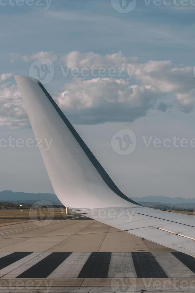 Aussicht von das Bullauge - - Flügel von ein Flugzeug nehmen aus über das Runway beim hoch Geschwindigkeit während das Sonnenuntergang. das Land ist Laufen unter das Flügel.. foto