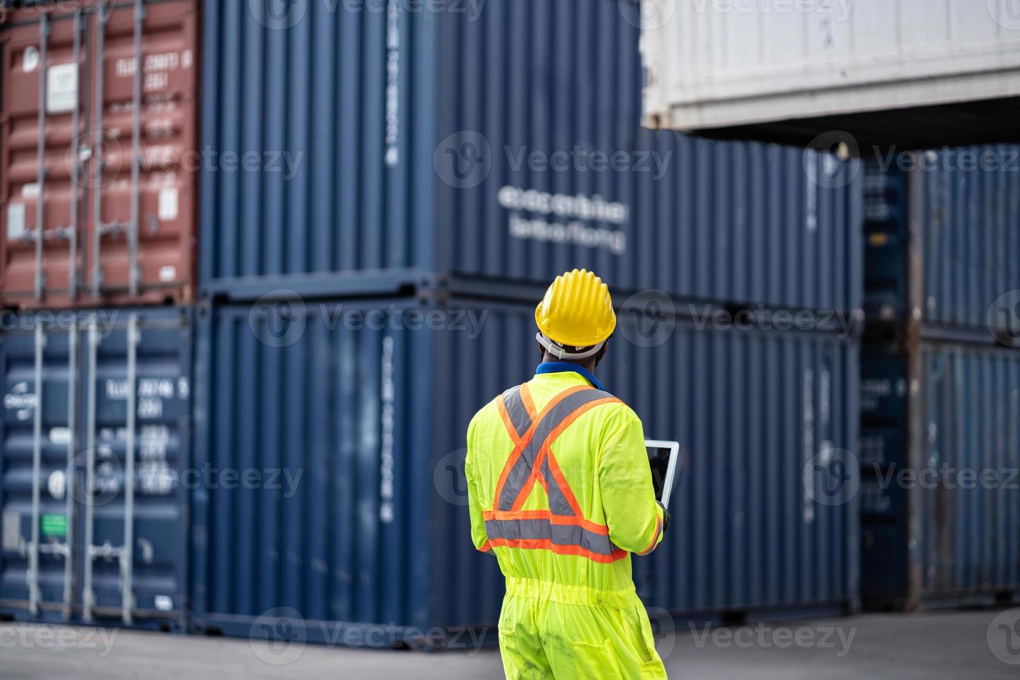 afrikanisch Techniker Dock Arbeiter im schützend Sicherheit Overall Uniform und mit Helm und verwenden Laptop Computer beim Ladung Container Versand Lagerhaus. Transport Import Export logistisch industriell foto