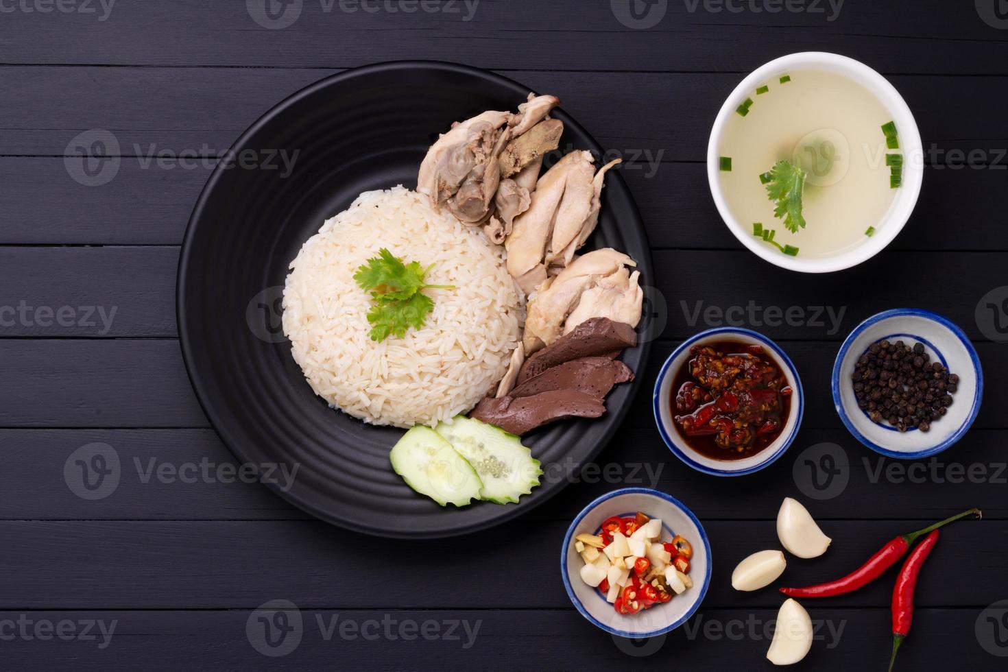 hainanese Hähnchen Reis auf ein schwarz hölzern Tabelle Hintergrund gedämpft Hähnchen Reis mit Hähnchen Suppe, Saucen Gewürze asiatisch Essen Thailand China Singapur, oben Aussicht foto