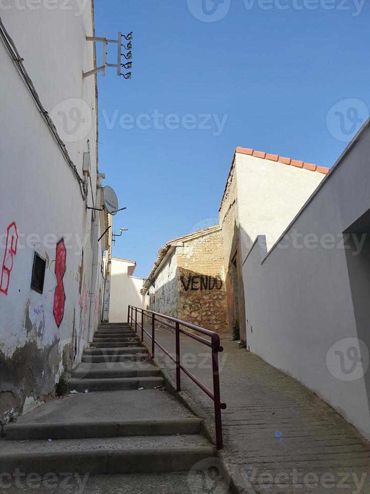 vernachlässigt Straße im ein Spanisch Stadt, Dorf mit Treppe und Graffiti auf das Wände von baufällig Gebäude foto