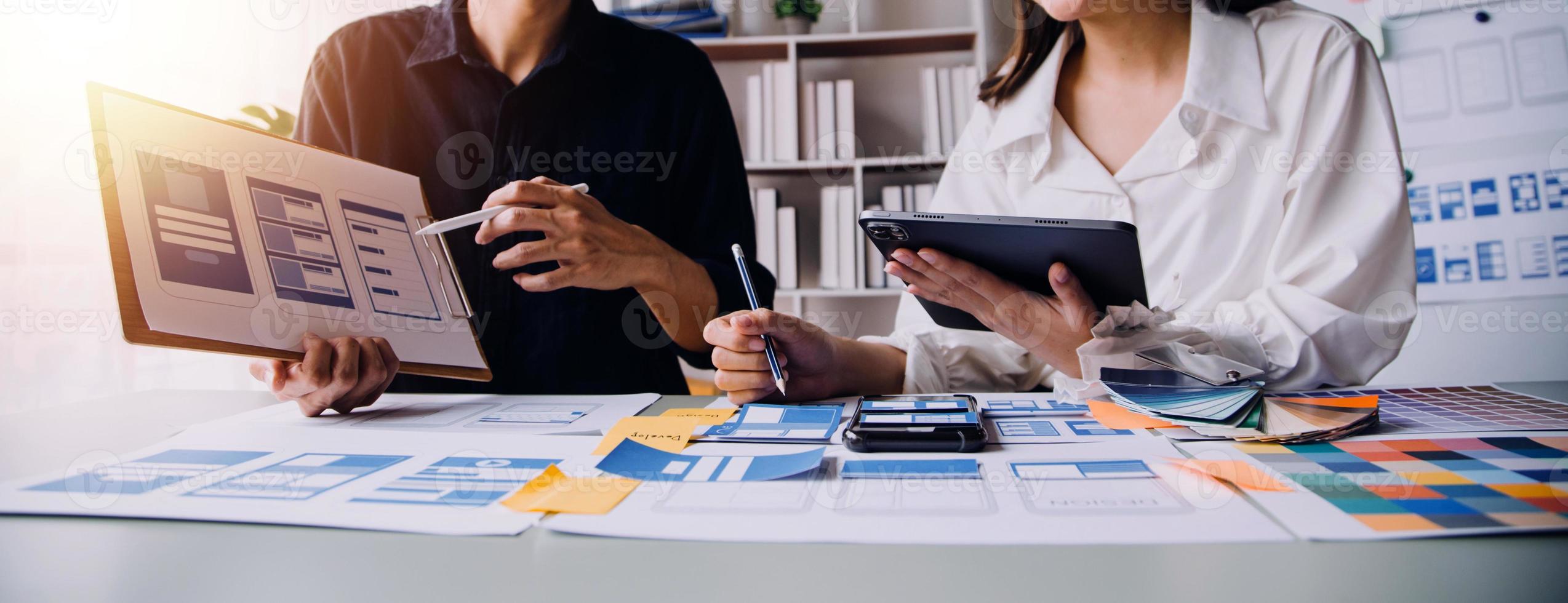 Nahaufnahme von UX-Entwicklern und UI-Designern beim Brainstorming über das Wireframe-Design der mobilen App-Schnittstelle auf dem Tisch mit Kundeninformationen und Farbcode in der Agentur für moderne digitale Entwicklung von Office.Creative foto