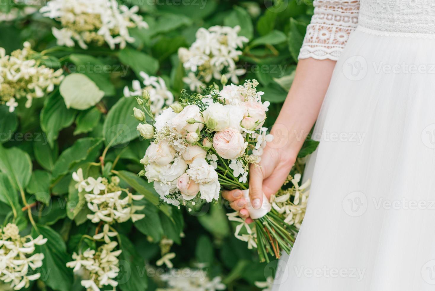 schöner zarter Hochzeitsblumenstrauß in den Händen der Braut foto