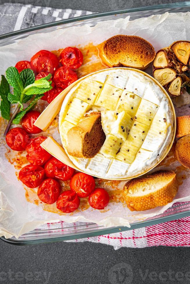 gebacken Sanft Käse Brie oder Camembert Tomate, Knoblauch und Kräuter Mahlzeit Essen Snack auf das Tabelle Kopieren Raum Essen Hintergrund rustikal oben Aussicht foto